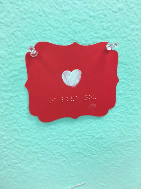 A red valentine with a white heart and Braille that says -'I love you'.